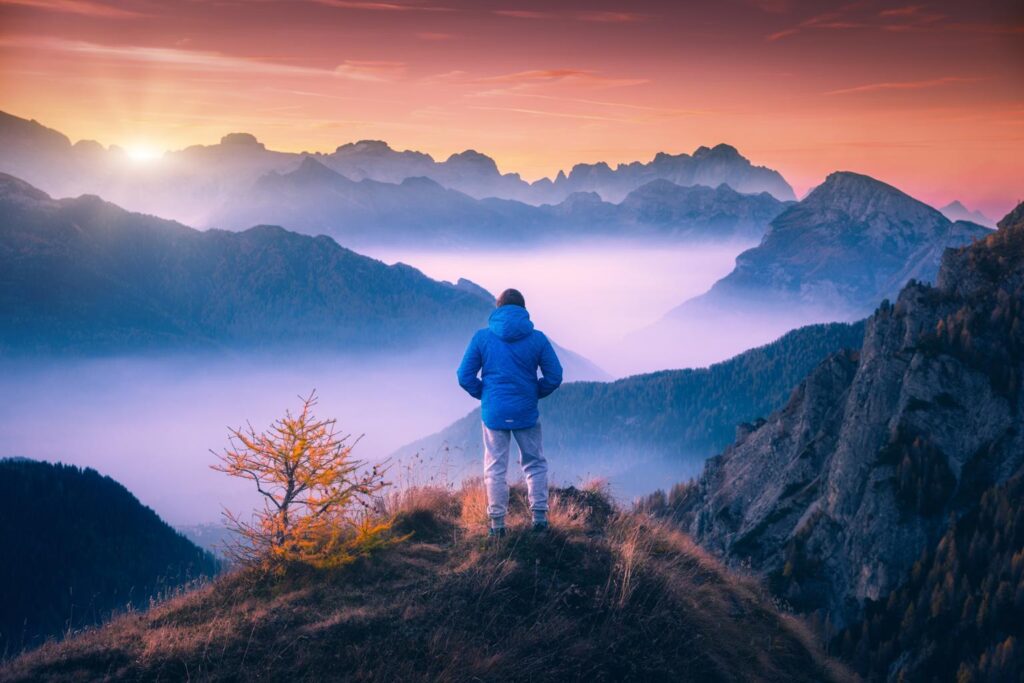 man on the mountain peak looking on mountain